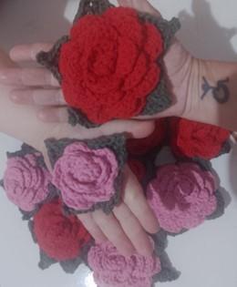 Em primeiro plano, a mão de mulher segura uma
rosa vermelha de crochê na palma; logo abaixo, a mão de outra mulher, de
pele branca e menor, segura uma flor cor de rosa de crochê. Ao fundo,
sobre um chão branco, encontram-se outras rosas vermelhas e cor de rosa
também feitas de crochê. Todas as flores possuem, ao redor, pétalas de
folhas verde-escuras também feitas de crochê